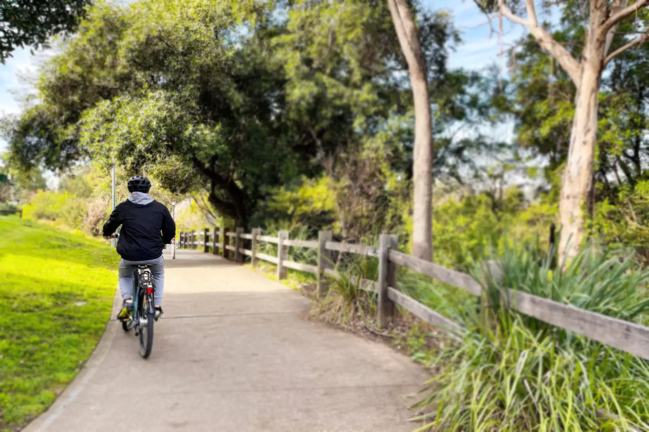 A young man is riding his bike through a park