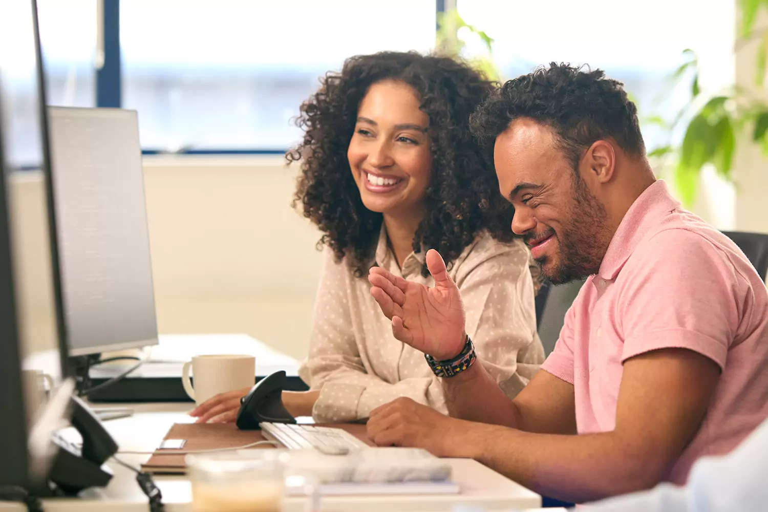A man with down syndrome and his care giver are working on a computer