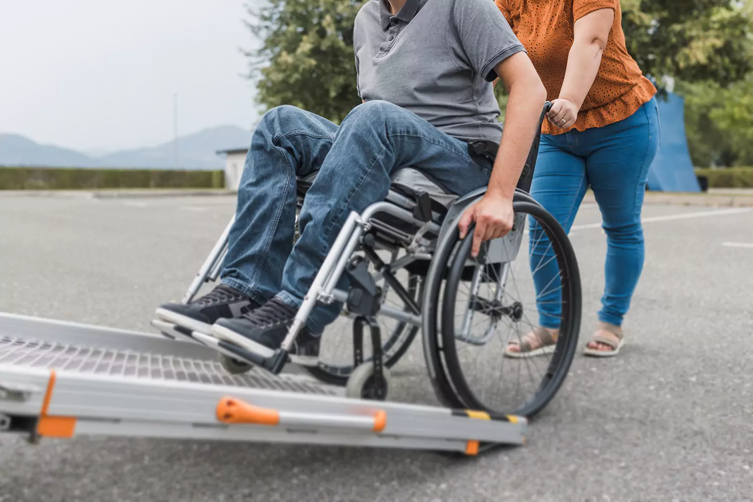A woman is assisting a man in a wheelchair into the back of a transport vehicle